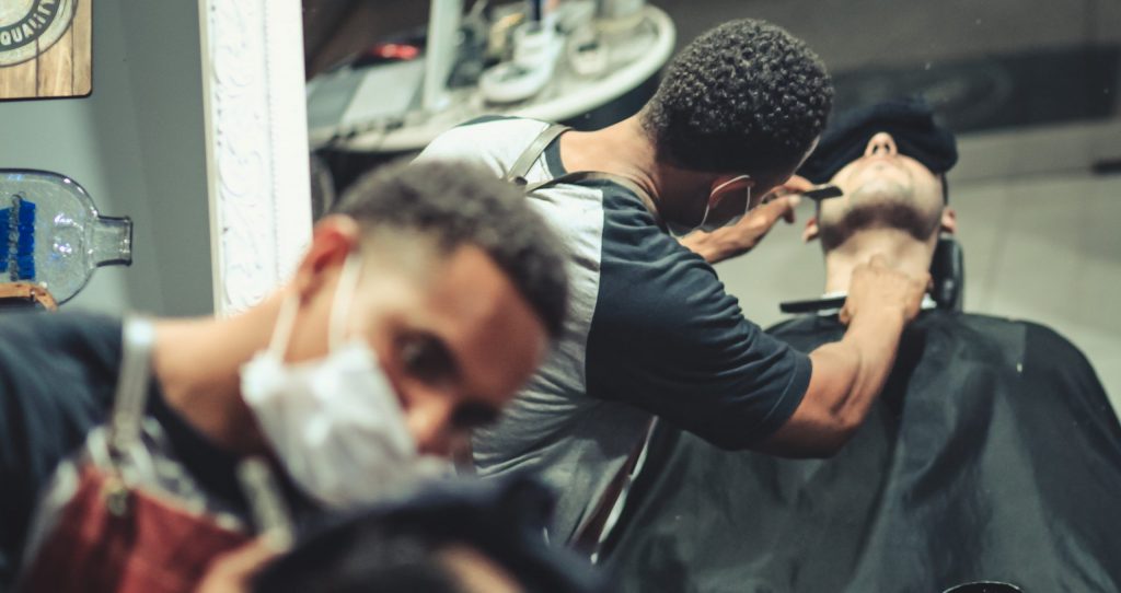 Barber serving customer with a mask