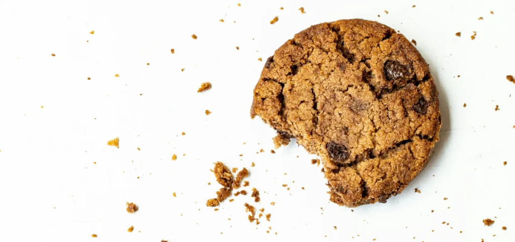 A real cookie with cookie crumbs on a table.

