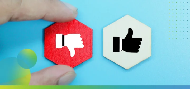 A person's fingers holding a thumbs down icon, while next to it there's a thumbs up icon card.