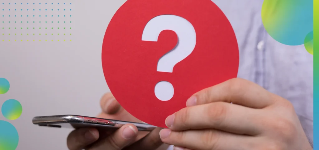 Sign of the question mark made of red paper and smartphone in the hands of a man.