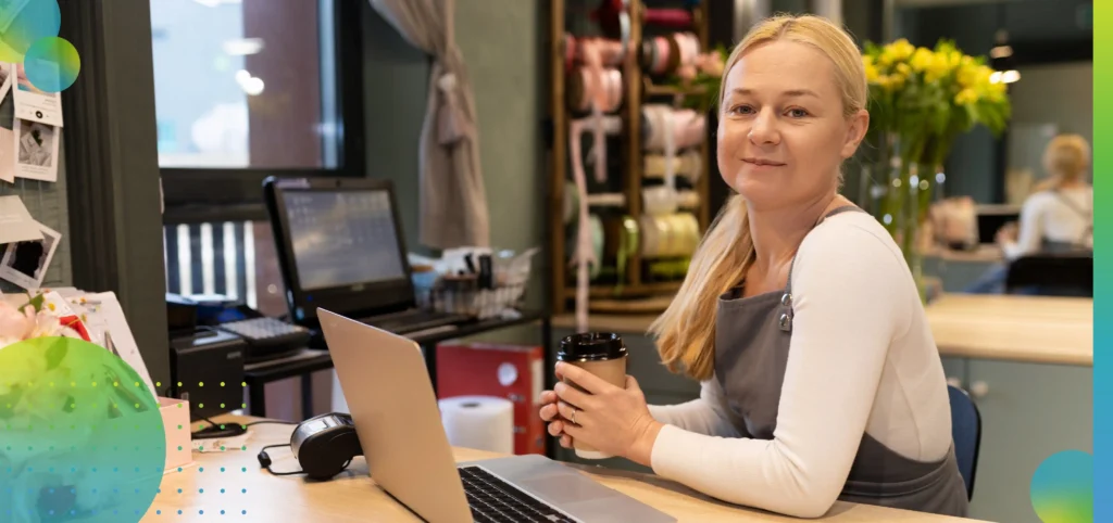 Friendly flower shop owner working at the computer with a smile on her face.