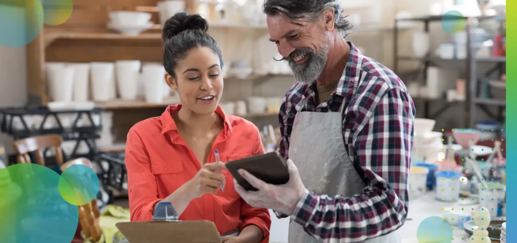 Male and female potter discussing over tablet.