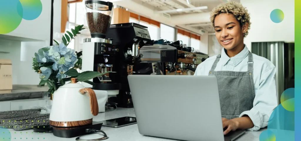 Woman working on her laptop in a coffee shop and smiling.