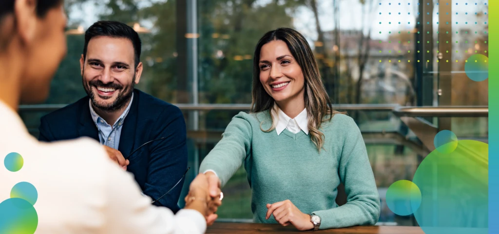 Smiling businesswoman handshaking with a female client, sitting at the office, elegantly dressed