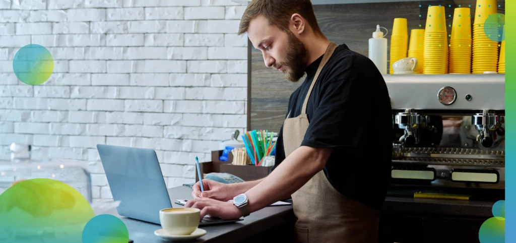 Owner coffee shop worker young male with laptop on the counter