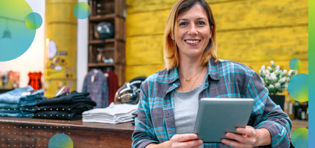 Banner of smiling blonde young female entrepreneur looking at camera in front of shop counter