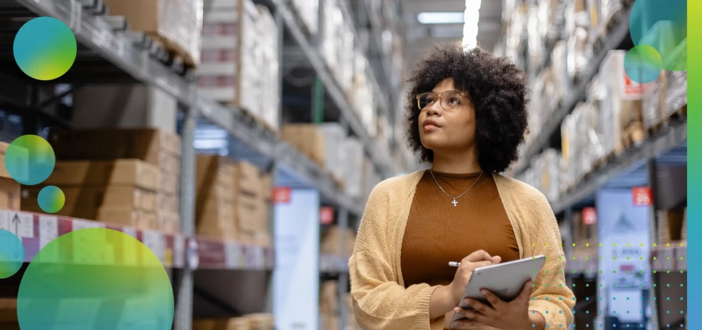 Young African American female looking at camera working in warehouse using digital