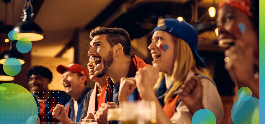 Excited supporters cheering for their winning team while watching live sports event in a pub